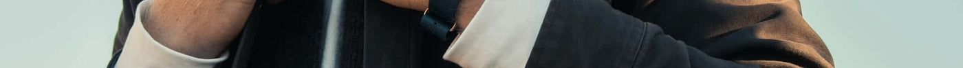 A stylish man showcasing luxury streetwear, highlighting a watch while pairing fashion pieces from different brands.
