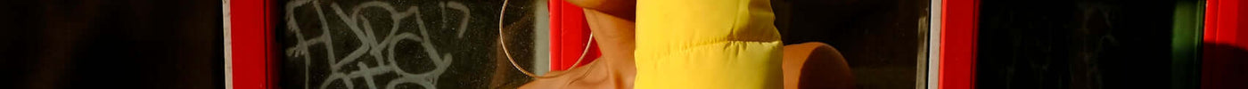 Young woman in a vibrant yellow puffer jacket embodies the evolution of global fashion brands in Barcelona style.