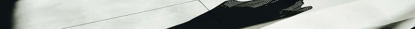 A person in a chic white dress casting a long shadow, illustrating core values of fashion brands in a minimalist space.