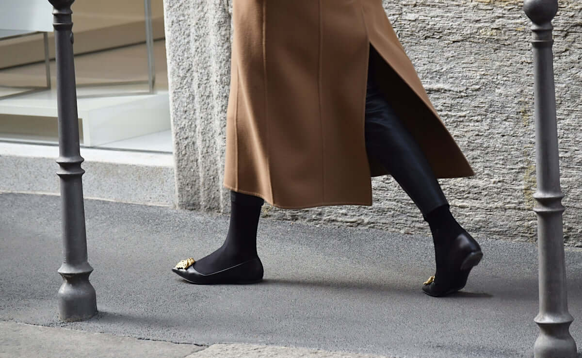 person wearing pair of black ballet flats