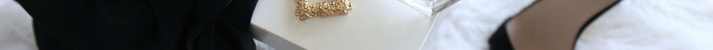 pair of gold-colored earrings on table and black ankle-strap pumps on area rug