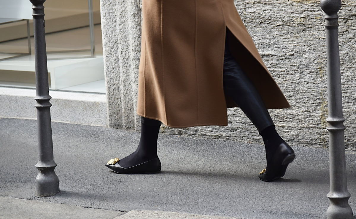 person wearing pair of black ballet flats