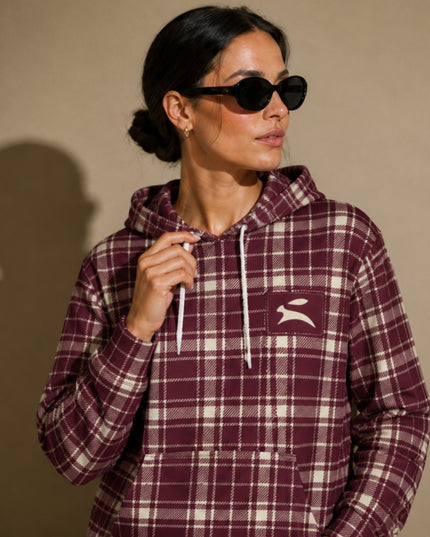 Close-up of the Grozavu hare patch on the Heritage Tartan Hoodie in Bordeaux, worn by the model