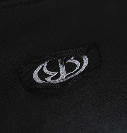 Close-up of Creative Vintage Hoodie – Loose Fit logo patch on black fabric.