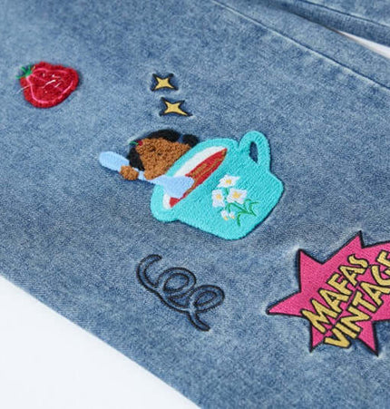 Close-up of cartoon patches on Cartoon Patch College Denim Pants featuring vibrant embroidery designs.