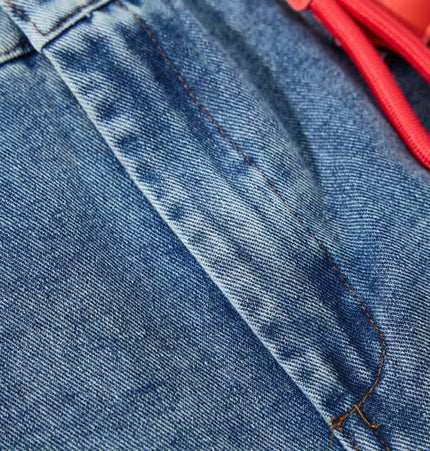 Close-up view of the Cartoon Patch College Denim Pants showing the fabric texture and drawstring detail.