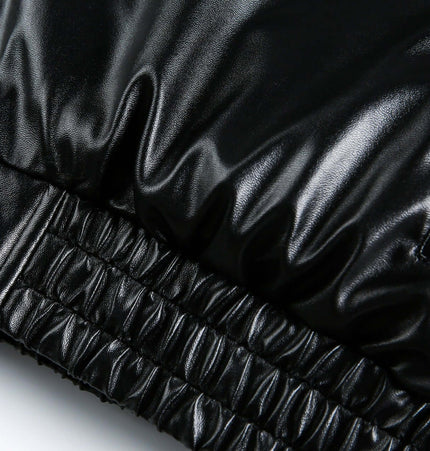 Detail of the oversized reversible hooded parka showcasing its sleek black faux leather material and elasticized hem.