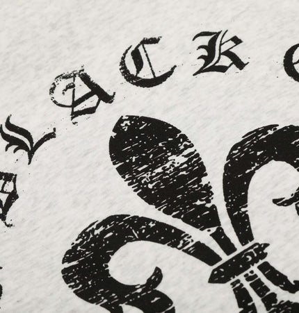 Close-up of the text and graphic design on a light gray fabric featuring a black fleur-de-lis and lettering.