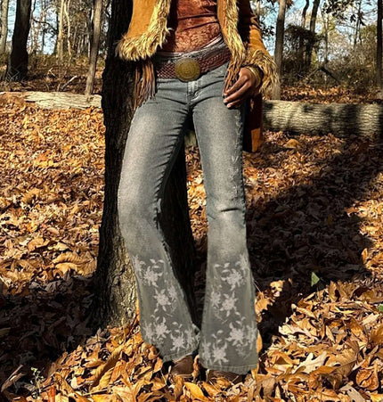 Woman wearing Retro Washed Slim Micro Flared Pants with floral detailing among autumn leaves.