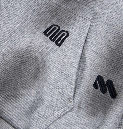 Distressed Letter Zip Hoodie - Loose Fit showcasing close-up of embroidered letters on soft gray fabric.