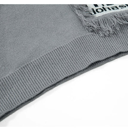 Close-up view of the hem and fringe detail on the Fringe Patchwork Knit Sweater – Loose Fit.