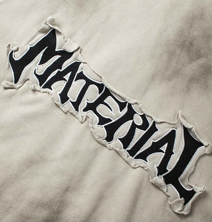 Close-up view of the embroidered 'MATERIAL' lettering on the Retro Patchwork Zip Up Hoodie – Loose Fit.