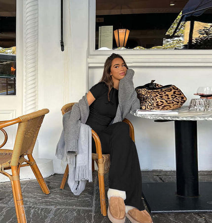 Woman in a black Pleated Short Sleeve Pants Set – Loose Fit, sitting at a cafe with a stylish bag and cozy sweater.