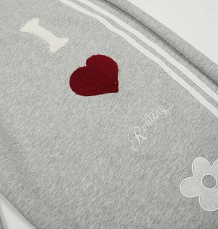 Towel Embroidery Heart Sweatpants featuring heart and flower embroidery details on grey fabric.