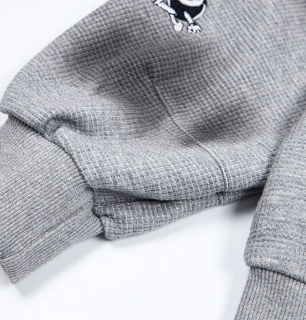 Close-up of the cuff detail on the Distressed Letter Zip Hoodie - Loose Fit, showcasing textured fabric and embroidered design.