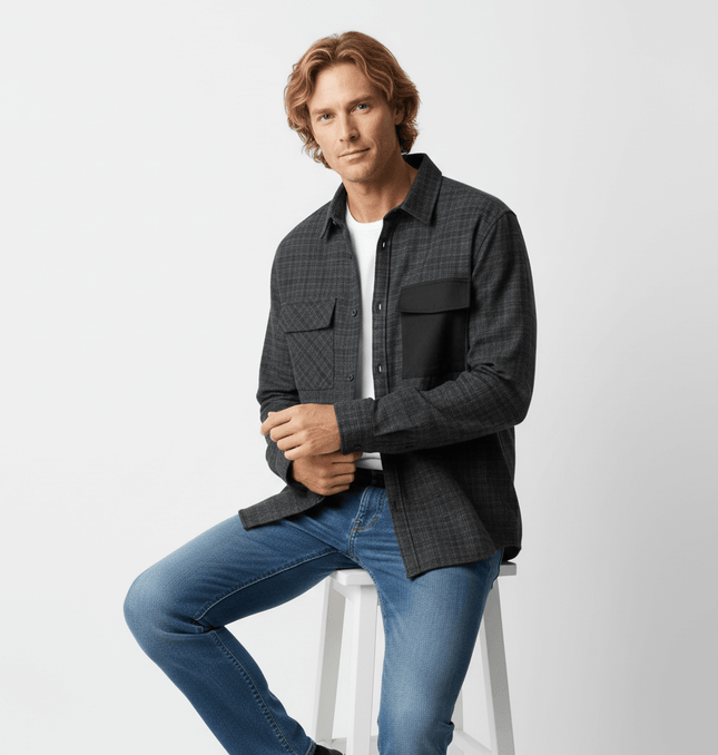 Color Block Plaid Shirt – Loose Fit worn by a model sitting on a stool, featuring black and dark plaid patterns.