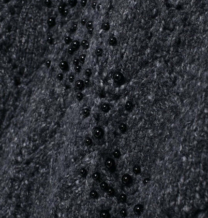 Close-up of the textured fabric of the Asymmetrical Off-Shoulder Knit Sweater, featuring hollow bead decoration.