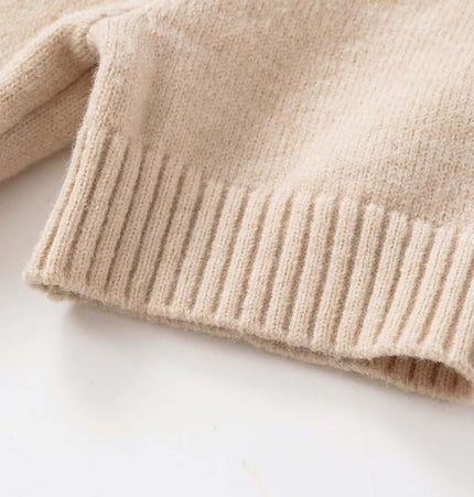 Detail view of the hem of the Round Neck Casual Knit Sweater, showcasing soft beige knit fabric.