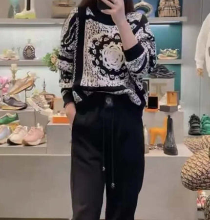 A woman models the Camellia Jacquard Beaded Knit Sweater with a round neckline and artistic pattern in a stylish setting.