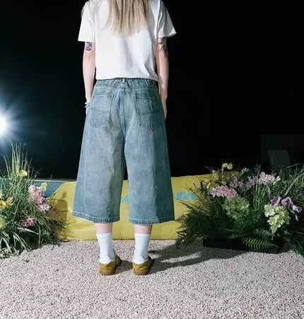 Person wearing Cartoon Dog Embroidered Denim Shorts featuring a trendy washed blue finish and relaxed fit.