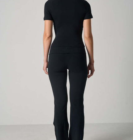 Back view of a woman wearing a Casual Fit Cotton Jersey Yoga Set, featuring a short sleeve crop top and high-waist long flare pants.