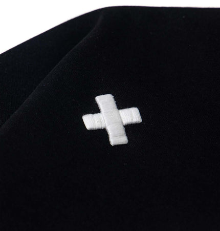 Close-up of the cross embroidery on the Cross Embroidered Hoodie – Loose Fit in black.