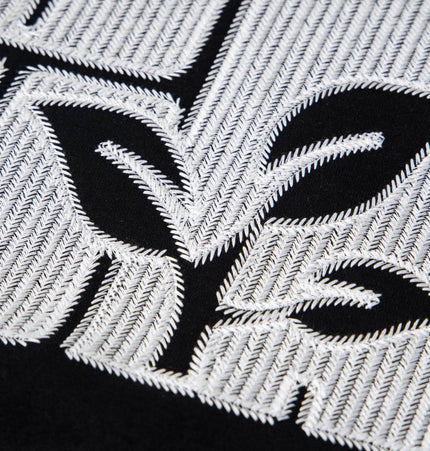 Close-up of cross embroidered detail on the Cross Embroidered Hoodie – Loose Fit, showcasing intricate stitching and design.