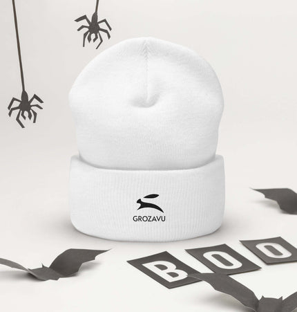 Cuffed Beanie displayed with Halloween decorations, showcasing a cozy white design with a logo.