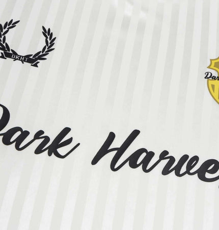 Close-up of a white striped fabric featuring text "Dark Harvest" and a yellow shield design with laurel leaves.