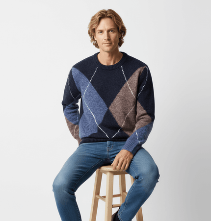 Man wearing a Diamond Pattern Knit Sweater with blue and brown diamond patterns, sitting on a stool.