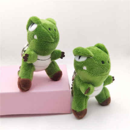 Green Dinosaur Plush Keychain set showing two cute green dinosaur plush figures on a pink background.