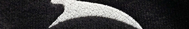 Extreme macro close-up of GROZAVU Black Hoodie showcasing premium heavyweight fabric weave, tactile ribbing, and razor-sharp graphic print detail