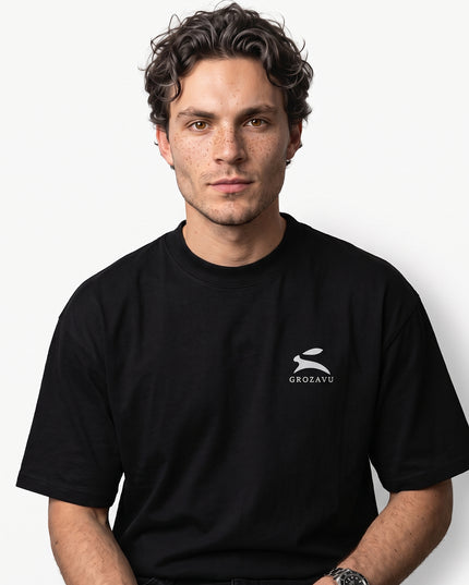 High-definition upper-body medium close-up zoom of model Jax wearing GROZAVU Black T-Shirt showcasing chest artwork and natural skin