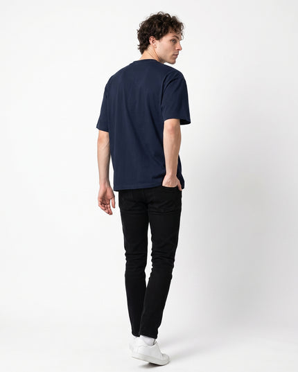 Full body rear view of model Jax wearing GROZAVU Dark Navy T-Shirt showcasing rear garment structure and back artwork
