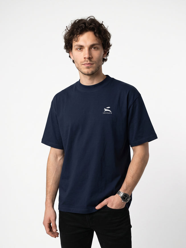 Dynamic 3/4 angled upper-body zoom of model Jax wearing GROZAVU Dark Navy T-Shirt highlighting garment drape, fit, and side profile