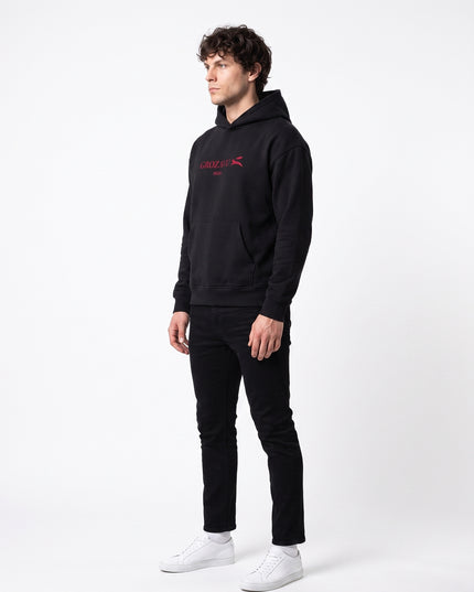 Editorial left-side profile view of model Jax wearing GROZAVU SS26 Black Hoodie highlighting left side silhouette, sleeve drape, and natural facial profile