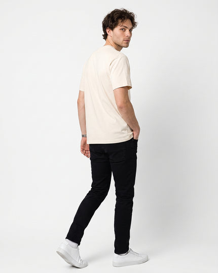 Full body rear view of model Jax wearing GROZAVU SS26 Off-White T-Shirt showcasing rear garment structure and back artwork