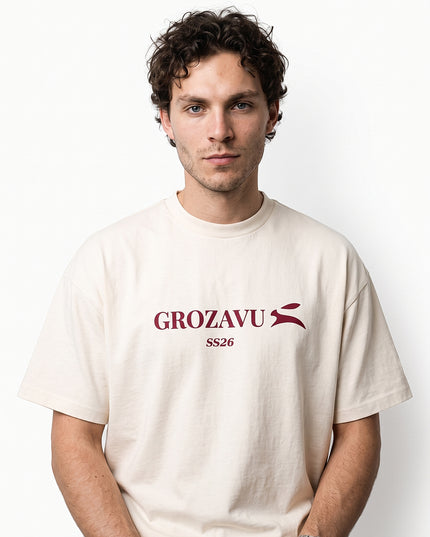 High-definition upper-body medium close-up zoom of model Jax wearing GROZAVU SS26 Off-White T-Shirt showcasing chest artwork and natural skin