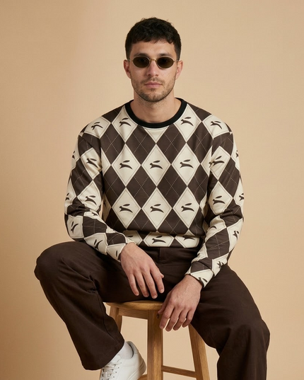 Model seated in the Hare Argyle Sweatshirt in Cocoa, showing the hare argyle on the chest and sleeves