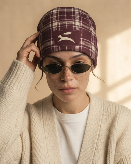 Model adjusting the Heritage Tartan Beanie in Bordeaux, styled with a cream cardigan