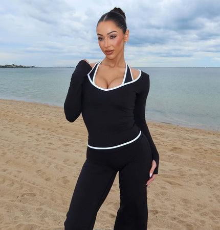 Long Sleeve Halter Neck Contrast Top model wearing black top by the beach, showcasing sleek minimalist design.