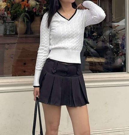 Long Sleeve VNeck Knit Top paired with a black pleated skirt in a stylish outdoor setting.