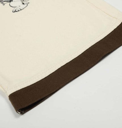 Close-up of the hem detail on Loose Fit Cartoon Patchwork Pants featuring brown cuff and cartoon embroidery.