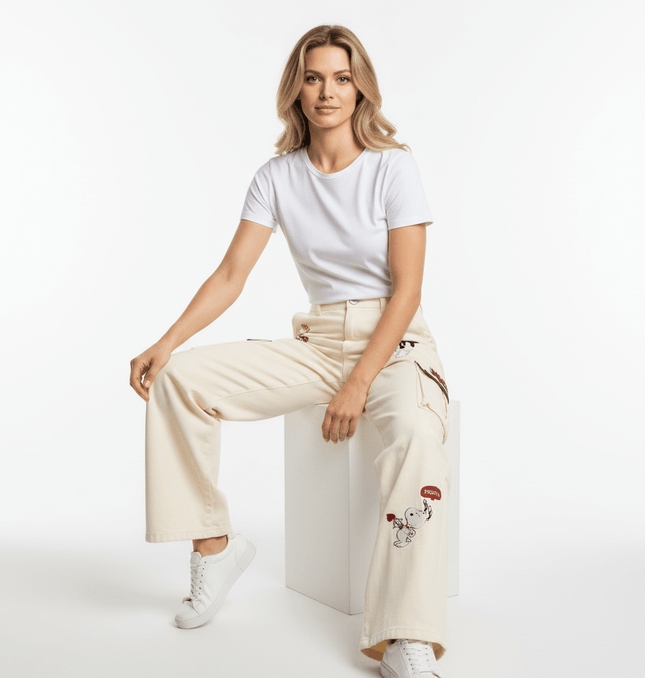 Loose Fit Cartoon Patchwork Pants worn by a model sitting casually on a white block, showcasing playful embroidery.
