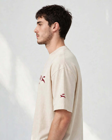 Side profile showing the drop-shoulder sleeve of the beige heavyweight tee