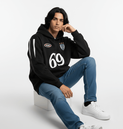 Oversized Hooded Sweatshirt – Loose Fit worn by a model sitting with stylish casual look in black and denim.