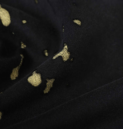 Close-up of the fabric texture featuring gold splashes on black background from the Splashing Ink Spliced Hooded Sweatshirt.