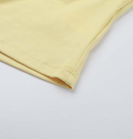 Detail of the square collar pleated two-piece set showing the soft fabric and stitching of the yellow top.